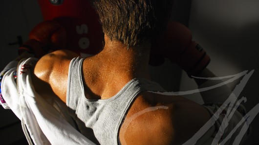 Fotografía de la espalda de un hombre, detalle del sudor, mientras boxea
