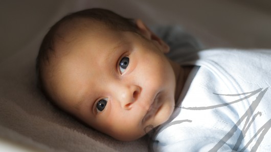 Fotografía en plano medio de un bebé de mes y medio tumbado