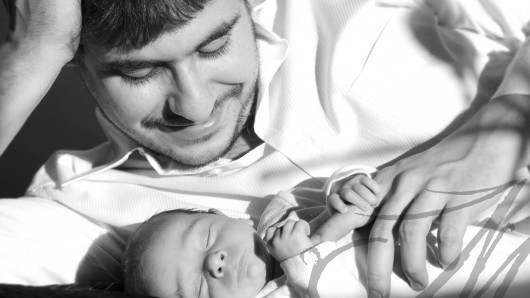 Fotografía en blanco y negro de un papá con su bebé agarradito de su mano