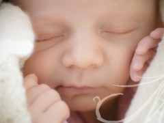Fotografía detalle de la carita de un bebé asomando en el arrullo