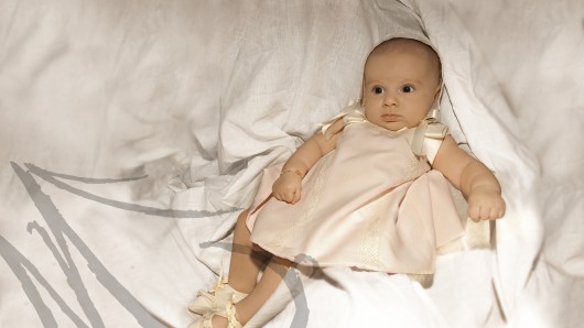 Fotografía de un bebé de cuatro meses, vestido de bautizo.