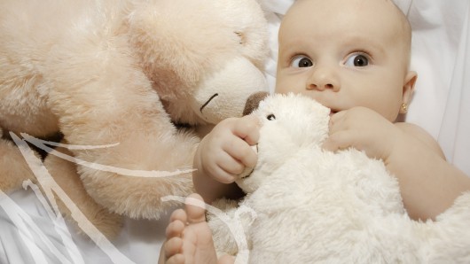 Fotografía de una bebé de cinco meses entre peluches