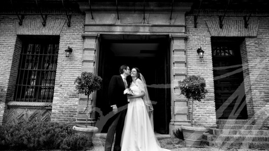 Fotografía de boda. Novios delante de la puerta de la casa de la finca.